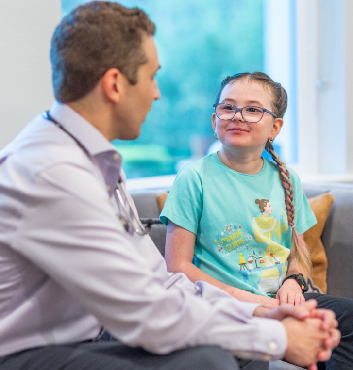 Doctor Weiss talking to a young girl with glasses and braids